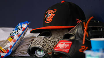 May 6, 2023; Atlanta, Georgia, USA; A detailed view of a Baltimore Orioles hat and glove in the dugout against the Atlanta Braves in the first inning at Truist Park.