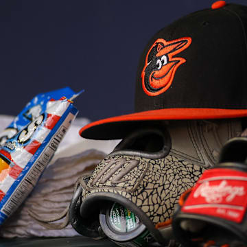 May 6, 2023; Atlanta, Georgia, USA; A detailed view of a Baltimore Orioles hat and glove in the dugout against the Atlanta Braves in the first inning at Truist Park.