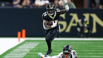 Nov 23, 2025; New Orleans, Louisiana, USA; New Orleans Saints running back Devin Neal (24) jumps over Atlanta Falcons cornerback Dee Alford (20) as he carries the ball during the second half at Caesars Superdome. Mandatory Credit: Stephen Lew-Imagn Images