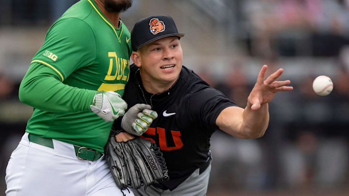 Oregon State left-handed pitcher Nelson Keljo throws to first for an out as he collides with Oregon infielder Dominic Hellman as the Oregon Ducks host the Oregon State Beavers on April 25, 2025, at PK Park in Eugene.