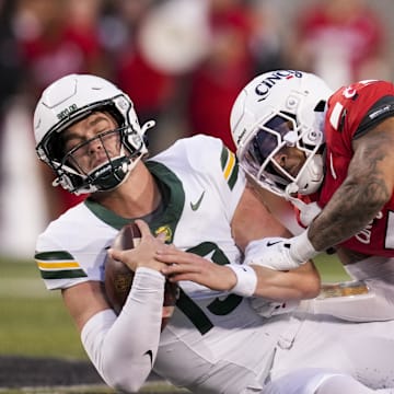 Oct 25, 2025; Cincinnati, Ohio, USA;  Baylor Bears quarterback Sawyer Robertson (13) runs with the ball as he is tackled by Cincinnati Bearcats safety Christian Harrison (5) in the second half at Nippert Stadium. Mandatory Credit: Aaron Doster-Imagn Images