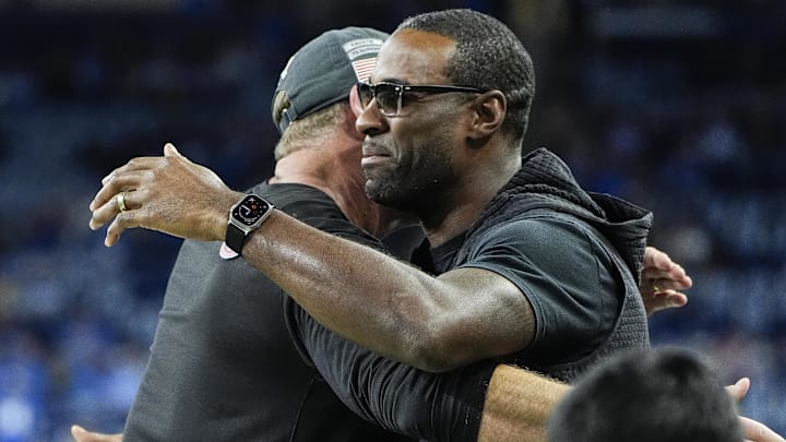 Nov 17, 2024; Detroit, MI, USA; Detroit Lions head coach Dan Campbell, left, hugs Calvin Johnson before the game between Detroit Lions and Jacksonville Jaguars at Ford Field in Detroit on Sunday, Nov. 17, 2024. Mandatory Credit: Junfu Han/USA TODAY Network via Imagn Images 