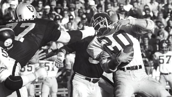 Dec 29, 1974; Oakland, CA, USA; FILE PHOTO; Oakland Raiders defensive end Bubba Smith (77) grabs the facemask of Pittsburgh Steelers running back Rocky Bleier (20) during the 1974 AFC Championship game at the Oakland Coliseum. Mandatory Credit: Malcolm Emmons-USA TODAY Sports