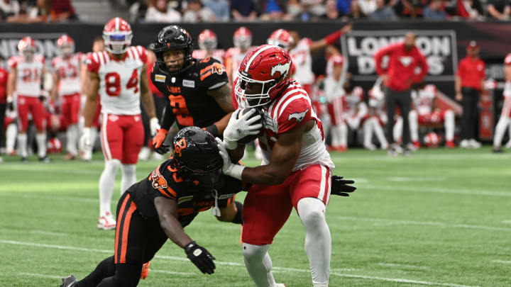 Jun 15, 2024; Vancouver, British Columbia, CAN; Calgary Stampeders running back Dedrick Mills (26) tackled by BC Lions defensive back Emmanuel Rugamba (33) during the second half at BC Place. Mandatory Credit: Simon Fearn-USA TODAY Sports