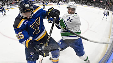Jan 27, 2025; St. Louis, Missouri, USA;  St. Louis Blues center Jordan Kyrou (25) and Vancouver Canucks center Pius Suter (24) battle for the puck during the first period at Enterprise Center. Mandatory Credit: Jeff Curry-Imagn Images