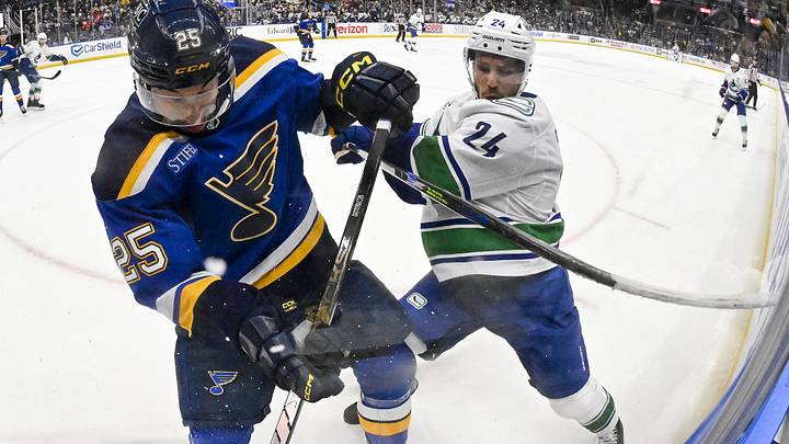 Jan 27, 2025; St. Louis, Missouri, USA;  St. Louis Blues center Jordan Kyrou (25) and Vancouver Canucks center Pius Suter (24) battle for the puck during the first period at Enterprise Center. Mandatory Credit: Jeff Curry-Imagn Images