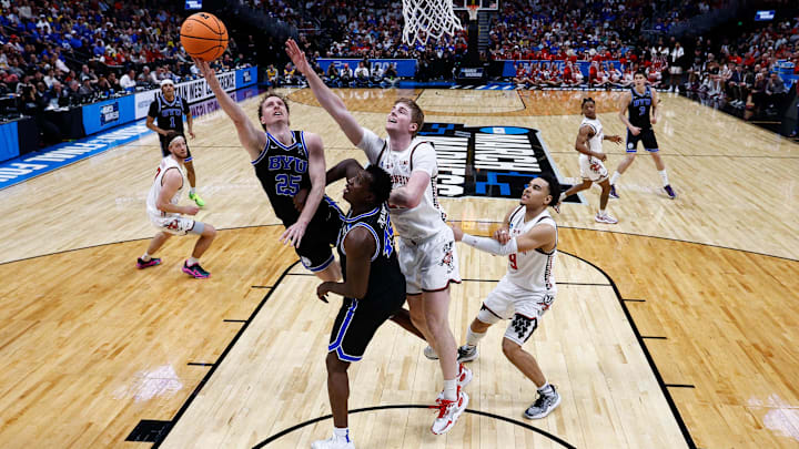 Mar 22, 2025; Denver, CO, USA; Brigham Young Cougars guard Dawson Baker (25) drives to the net against Wisconsin Badgers forward Steven Crowl (22) as center Fousseyni Traore (45) defends and guard John Tonje (9) looks on in the second half at Ball Arena. Mandatory Credit: Isaiah J. Downing-Imagn Images