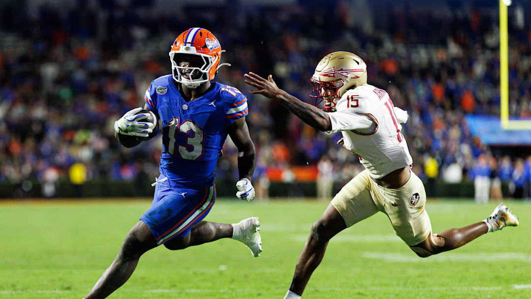 Nov 29, 2025; Gainesville, Florida, USA; Florida Gators running back Jadan Baugh (13) rushes with the ball past Florida State Seminoles defensive back Shamar Arnoux (15) during the second half at Ben Hill Griffin Stadium. Mandatory Credit: Matt Pendleton-Imagn Images