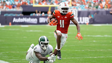 Sep 18, 2021; Miami Gardens, Florida, USA; Miami Hurricanes wide receiver Charleston Rambo (11) breaks the tackle of Michigan State Spartans safety Michael Dowell (7) during the second half at Hard Rock Stadium. Mandatory Credit: Jasen Vinlove-Imagn Images