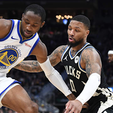 Jan 13, 2024; Milwaukee, Wisconsin, USA; Golden State Warriors forward Jonathan Kuminga (00) drives against Milwaukee Bucks guard Damian Lillard (0) in the first half at Fiserv Forum. Mandatory Credit: Michael McLoone-Imagn Images