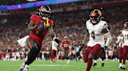 Jan 12, 2025; Tampa, Florida, USA; Tampa Bay Buccaneers running back Bucky Irving (7) makes a touchdown catch against Washington Commanders linebacker Frankie Luvu (4) during the third quarter of a NFC wild card playoff at Raymond James Stadium. Mandatory Credit: Nathan Ray Seebeck-Imagn Images
