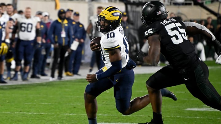 Oct 21, 2023; East Lansing, Michigan, USA;  Michigan Wolverines quarterback Alex Orji (10) runs around the end, pursued by Michigan State Spartans defensive lineman Jalen Thompson (55) in the fourth quarter at Spartan Stadium. Mandatory Credit: Dale Young-USA TODAY Sports