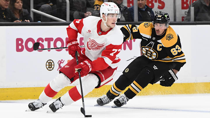 Dec 3, 2024; Boston, Massachusetts, USA; Detroit Red Wings defenseman Simon Edvinsson (77) controls the puck against Boston Bruins left wing Brad Marchand (63) during the third period at the TD Garden. Mandatory Credit: Brian Fluharty-Imagn Images
