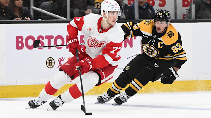 Dec 3, 2024; Boston, Massachusetts, USA; Detroit Red Wings defenseman Simon Edvinsson (77) controls the puck against Boston Bruins left wing Brad Marchand (63) during the third period at the TD Garden. Mandatory Credit: Brian Fluharty-Imagn Images