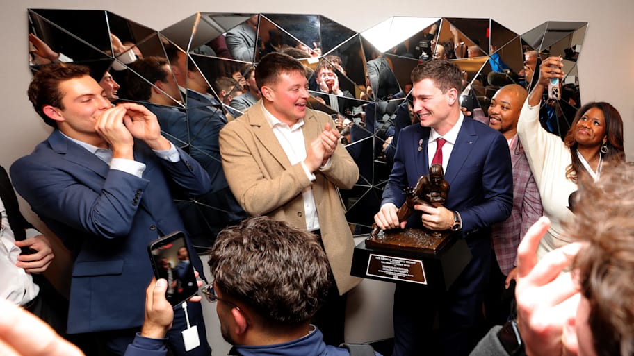 Hoosiers quarterback Fernando Mendoza holds the Heisman Trophy as he celebrates with teammates.