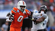 Dec 28, 2024; Orlando, FL, USA; Miami Hurricanes wide receiver Joshisa Trader (0) stiff arms Iowa State Cyclones defensive back Myles Purchase (5) while running for a touchdown during the first half at Camping World Stadium. Mandatory Credit: Jasen Vinlove-Imagn Images