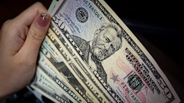 In this photo illustration, a person holds 1, 10, 20, and 50...