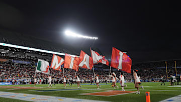 Dec 28, 2024; Orlando, FL, USA; Miami Hurricanes cheerleaders run on the field with flags after a touchdown against the Iowa State Cyclones during the second half at Camping World Stadium. Mandatory Credit: Jasen Vinlove-Imagn Images