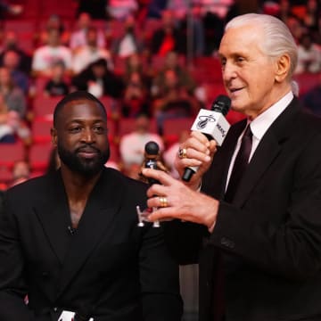 Jan 14, 2024; Miami, Florida, USA; Miami Heat president Pat Riley (R) shows former player Dwayne Wade (L) a bobble head while announcing that a statue in the likeness of Wade will be erected outside the arena in 2025, during halftime of the game between the Miami Heat and the Charlotte Hornets at Kaseya Center. Mandatory Credit: Jasen Vinlove-USA TODAY Sports
