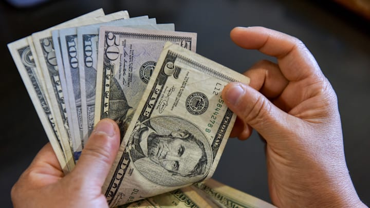 In this photo illustration, a person seen holding 5, 50, and... In this photo illustration, a person seen holding 5, 50, and...