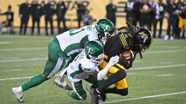 Jun 16, 2024; Hamilton, Ontario, CAN; Hamilton Tiger Cats wide receiver Shemar Bridges (17) is tackled by Saskatchewan Rough Riders defensive back Marcus Sayles (8) and defensive lineman Maalik Carney (11) in the third quarter at Tim Hortons Field. Mandatory Credit: Gerry Angus-USA TODAY Sports