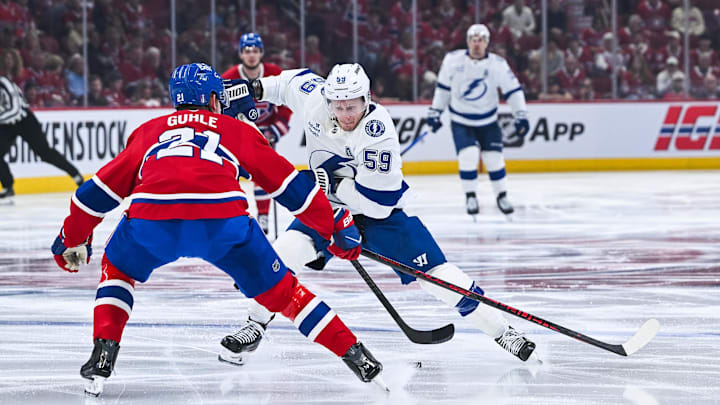 Apr 26, 2026; Montreal, Quebec, CAN; Tampa Bay Lightning center Jake Guentzel (59) plays the puck against Montreal Canadiens defenseman Kaiden Guhle (21) during the second period in game four of the first round of the 2026 Stanley Cup Playoffs at Bell Centre. Mandatory Credit: David Kirouac-Imagn Images