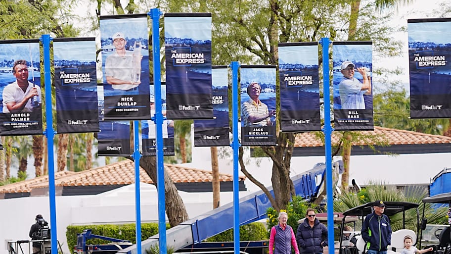 Spectators walk amongst banners of previous winners of the American Express.
