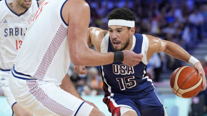 Jul 28, 2024; Villeneuve-d'Ascq, France; United States guard Devin Booker (15) drives against Serbia power forward Nikola Jokic (15) in the first quarter during the Paris 2024 Olympic Summer Games at Stade Pierre-Mauroy. Mandatory Credit: John David Mercer-USA TODAY Sports