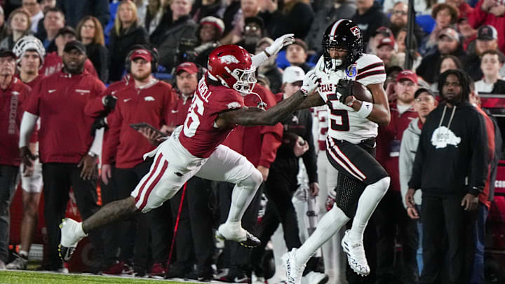 Texas Tech's Caleb Douglas (5) runs with the ball as Arkansas' Miguel Mitchell (16) attempts to tackle him during the AutoZone Liberty Bowl between Arkansas and Texas Tech in Memphis, Tenn., on Friday, December 27, 2024.