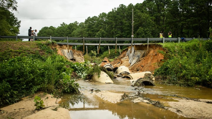 Residents and a TV news crew check out the dam that broke on Siple Avenue in the Rayconda neighborhood on Thursday, Aug. 8, 2024. The same dam broke during Hurricane Matthew.