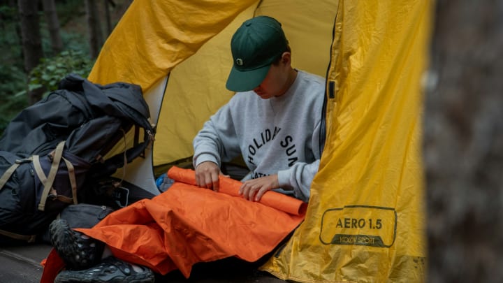 Camper Rolling up a Sleeping Pad