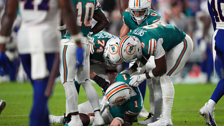 Miami Dolphins offensive tackle Liam Eichenberg (74) and tight end Jonnu Smith (9) attend to quarterback Tua Tagovailoa (1) after an apparent injury during the second half against the Buffalo Bills at Hard Rock Stadium.