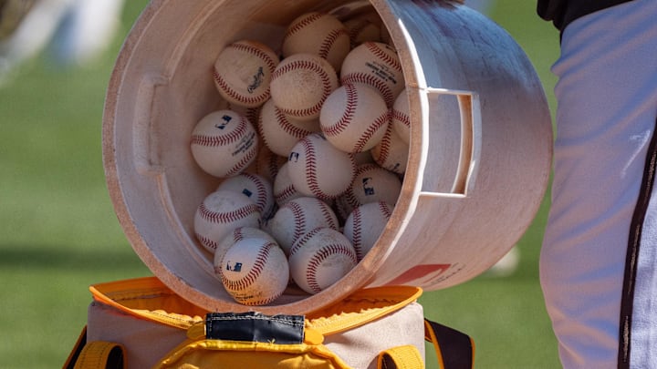 Feb 18, 2024; Peoria, AZ, USA; A general view as a coach for the San Diego Padres pours a bucket of baseballs into the to go bag during a workout day at Peoria Sports Complex. Mandatory Credit: Allan Henry-Imagn Images