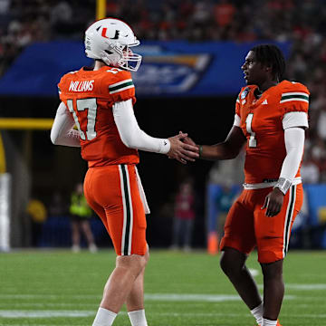 Dec 28, 2024; Orlando, FL, USA; Miami Hurricanes quarterback Emory Williams (17) shakes hands with quarterback Cam Ward (1) after a touchdown against the Iowa State Cyclones during the second half at Camping World Stadium. Mandatory Credit: Jasen Vinlove-Imagn Images