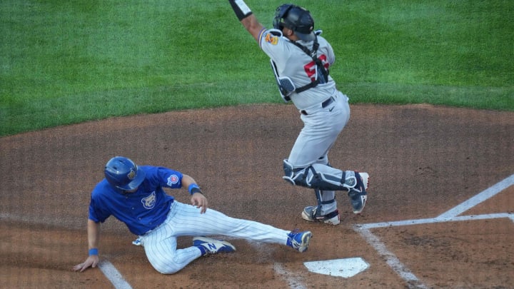 Iowa Cubs center fielder Darius Hill slides safely across home plate ahead of the tag by St. Paul