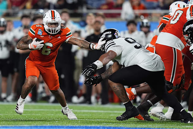 Miami Hurricanes running back Damien Martinez (6) stiff arms Iowa State Cyclones linebacker Cael Brezina (9).