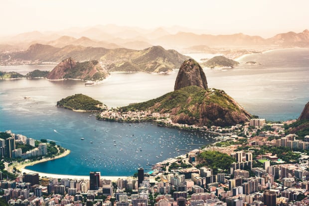 Overlooking the city of Rio de Janeiro you see many buildings and a lake.