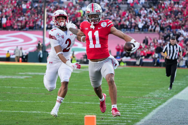 Wide receiver stiff arms defender headed for end zone near sideline.