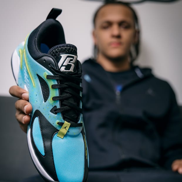 Paolo Banchero holds his blue sneakers.
