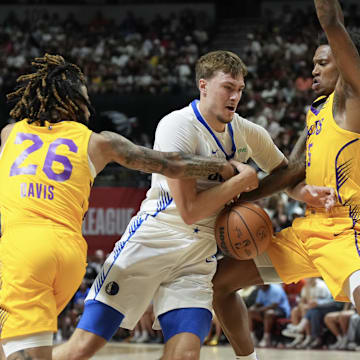Jul 10, 2025; Las Vegas, NV, USA; Dallas Mavericks forward Cooper Flagg (32) dribbles against Los Angeles Lakers guard RJ Davis (26) and guard DaJaun Gordon (45) in the first quarter of their game at Thomas & Mack Center. Mandatory Credit: Candice Ward-Imagn Images