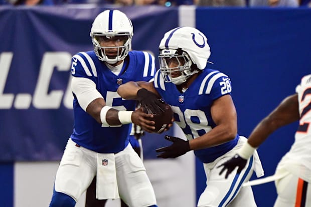 Indianapolis Colts quarterback Anthony Richardson hands the ball off to running back Jonathan Taylor in blue jerseys.