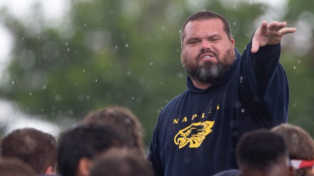 Naples football head coach Rick Martin speaks to his team during practice