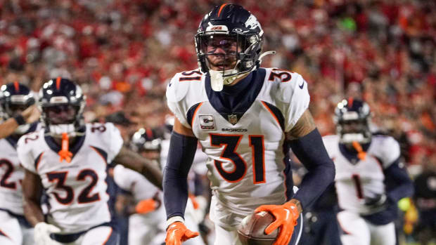 Denver Broncos safety Justin Simmons (white jersey with dark blue sleeves/helmet) celebrates after making a big play.