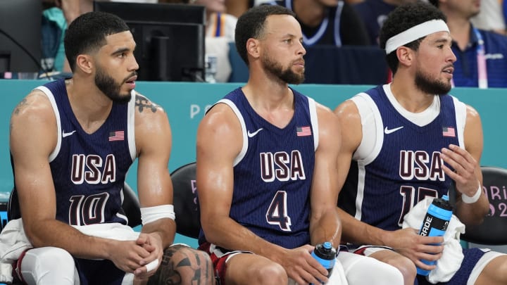 Aug 3, 2024; Villeneuve-d'Ascq, France; United States small forward Jayson Tatum (10), shooting guard Stephen Curry (4), guard Devin Booker (15) and assistant coach Tyronn Lue on the bench in the third quarter against Puerto Rico during the Paris 2024 Olympic Summer Games at Stade Pierre-Mauroy. Mandatory Credit: John David Mercer-USA TODAY Sports