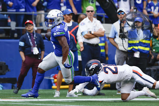 Seattle Seahawks running back Kenneth Walker III (9) breaks a tackle attempt by Denver Broncos cornerback Riley Moss (21).