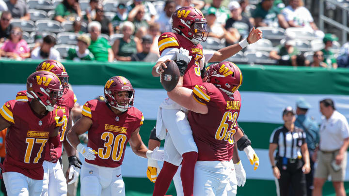 Aug 10, 2024; East Rutherford, New Jersey, USA; Washington Commanders quarterback Jayden Daniels (5) celebrates his touchdown with teammates during the first quarter against the New York Jets at MetLife Stadium. Mandatory Credit: Vincent Carchietta-USA TODAY Sports