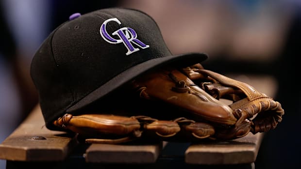Black Colorado Rockies hat on a brown mitt