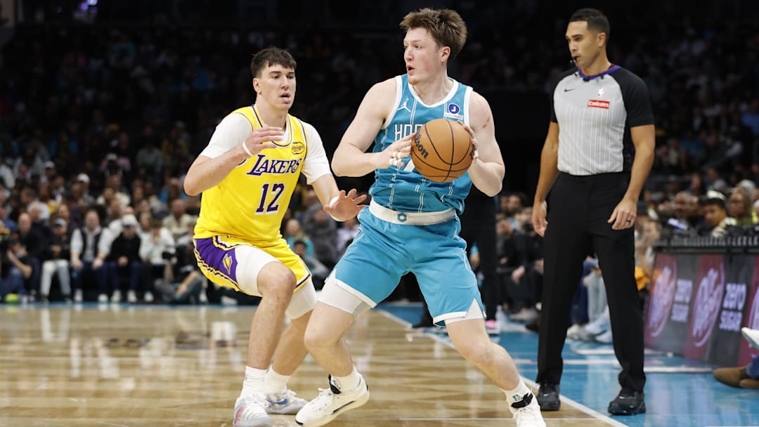 Nov 10, 2025; Charlotte, North Carolina, USA; Charlotte Hornets guard/forward Kon Knueppel (7) is guarded by Los Angeles Lakers forward Jake Laravia (12) during the second half at Spectrum Center. Mandatory Credit: Brian Westerholt-Imagn Images