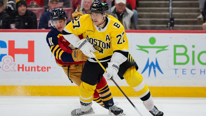 Feb 4, 2026; Sunrise, Florida, USA; Boston Bruins defenseman Hampus Lindholm (27) moves the puck against Florida Panthers right wing MacKie Samoskevich (11) during the first period at Amerant Bank Arena. Mandatory Credit: Sam Navarro-Imagn Images