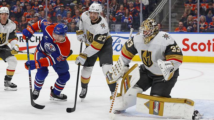 Edmonton Oilers forward Vasily Podkolzin (92) and Vegas Golden Knights defensemen Shea Theodore (27) look for a loose puck in front of goaltender Adin Hill (33)